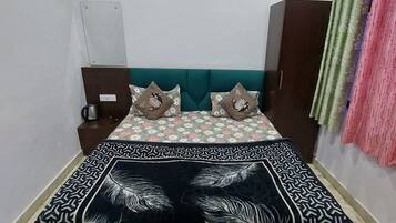 Un dormitorio con cama, mesita de noche, armario y cortina.