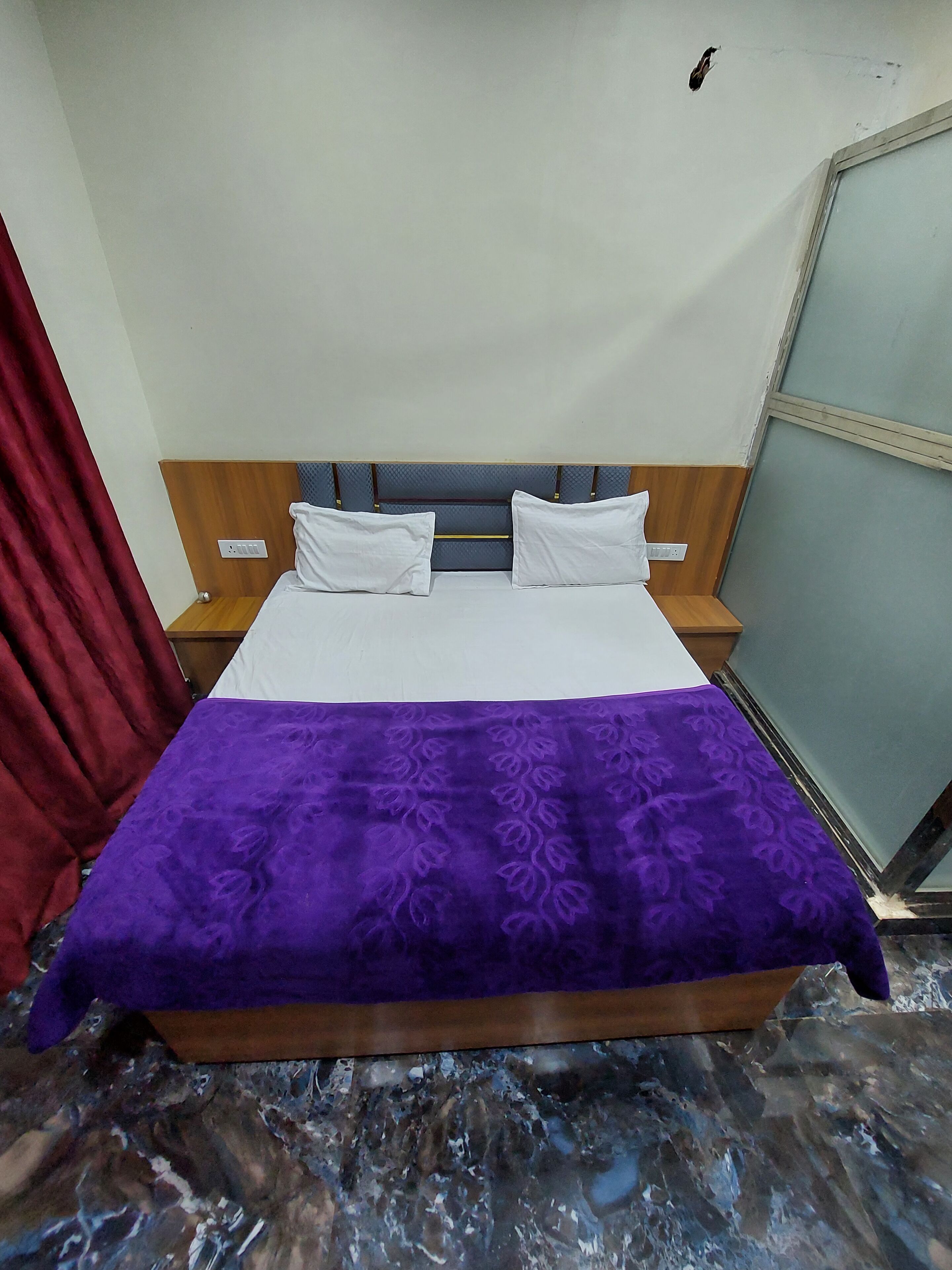A bed with a wooden headboard, two white pillows, and a purple bedspread.