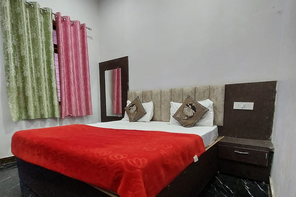 Un dormitorio con una cama, una mesita de noche, un espejo y un estante en la pared.