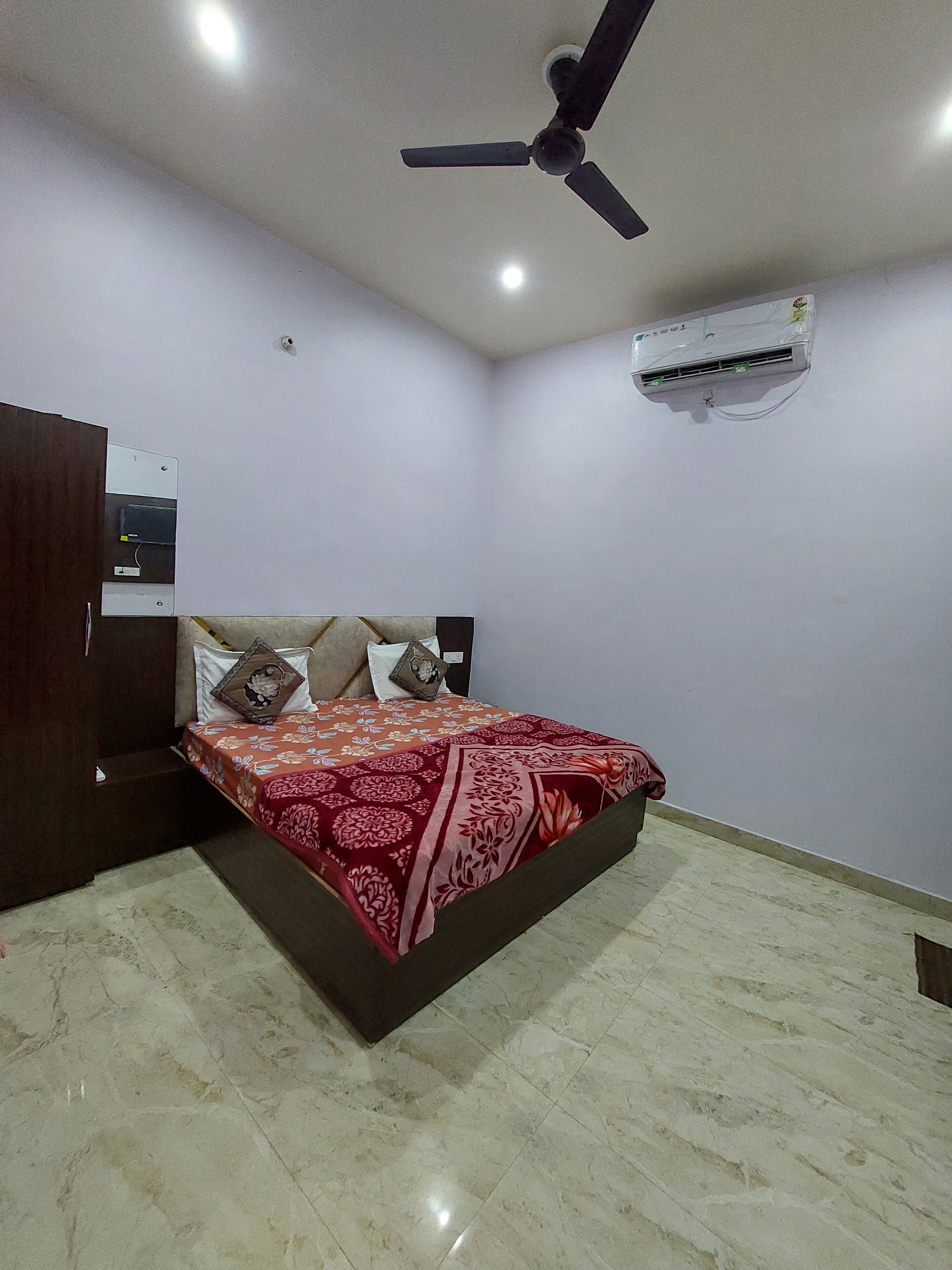 Un dormitorio con una cama, ventilador de techo, aire acondicionado y un armario de madera.