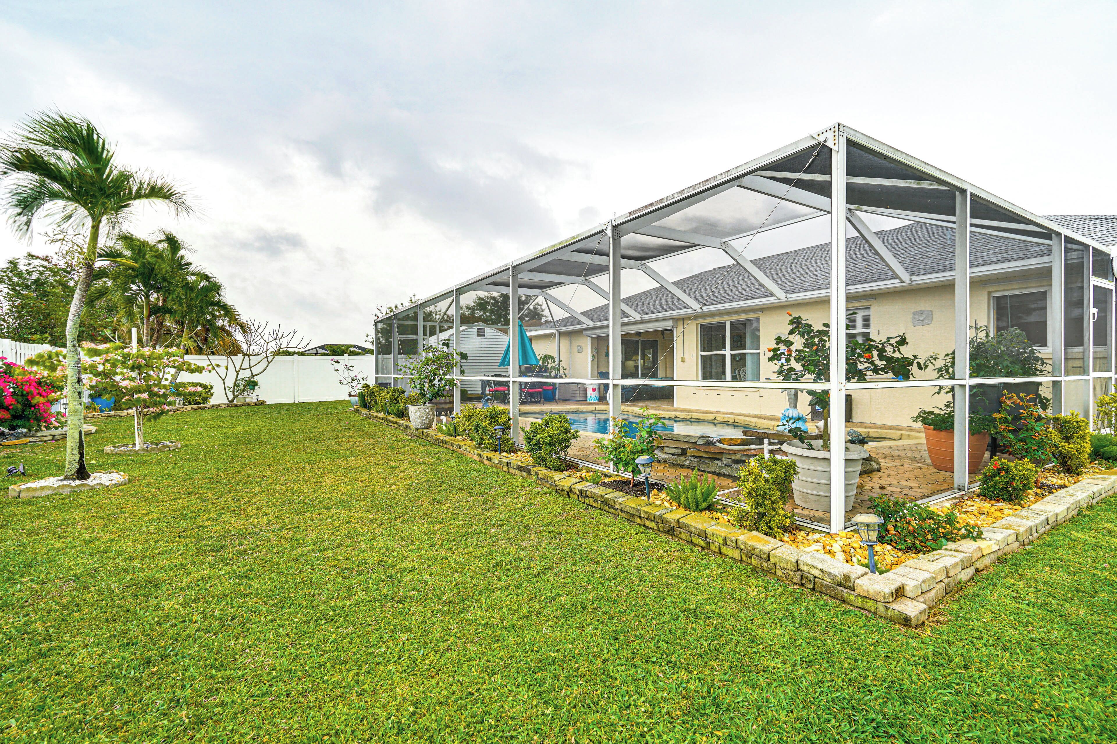 A house with a covered patio area, a swimming pool, and a well-maintained lawn.