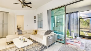 Ein modernes Wohnzimmer mit einem weißen Sofa, einem Couchtisch und einer Glastür, die auf einen Balkon führt.