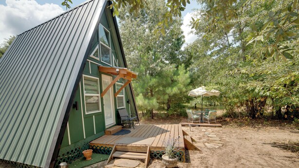 A small, green cabin with a wooden deck, a patio table, and chairs. - 7 Mi to Tyler State Park: 'A-Game' Cabin (Tyler)