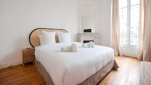 Ein Hotelzimmer mit einem großen Bett, einem Nachttisch, einem Spiegel, einem Kamin und einem Fenster mit Vorhängen.