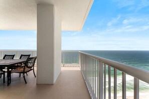 Un balcon avec une table et des chaises, donnant sur l’océan.