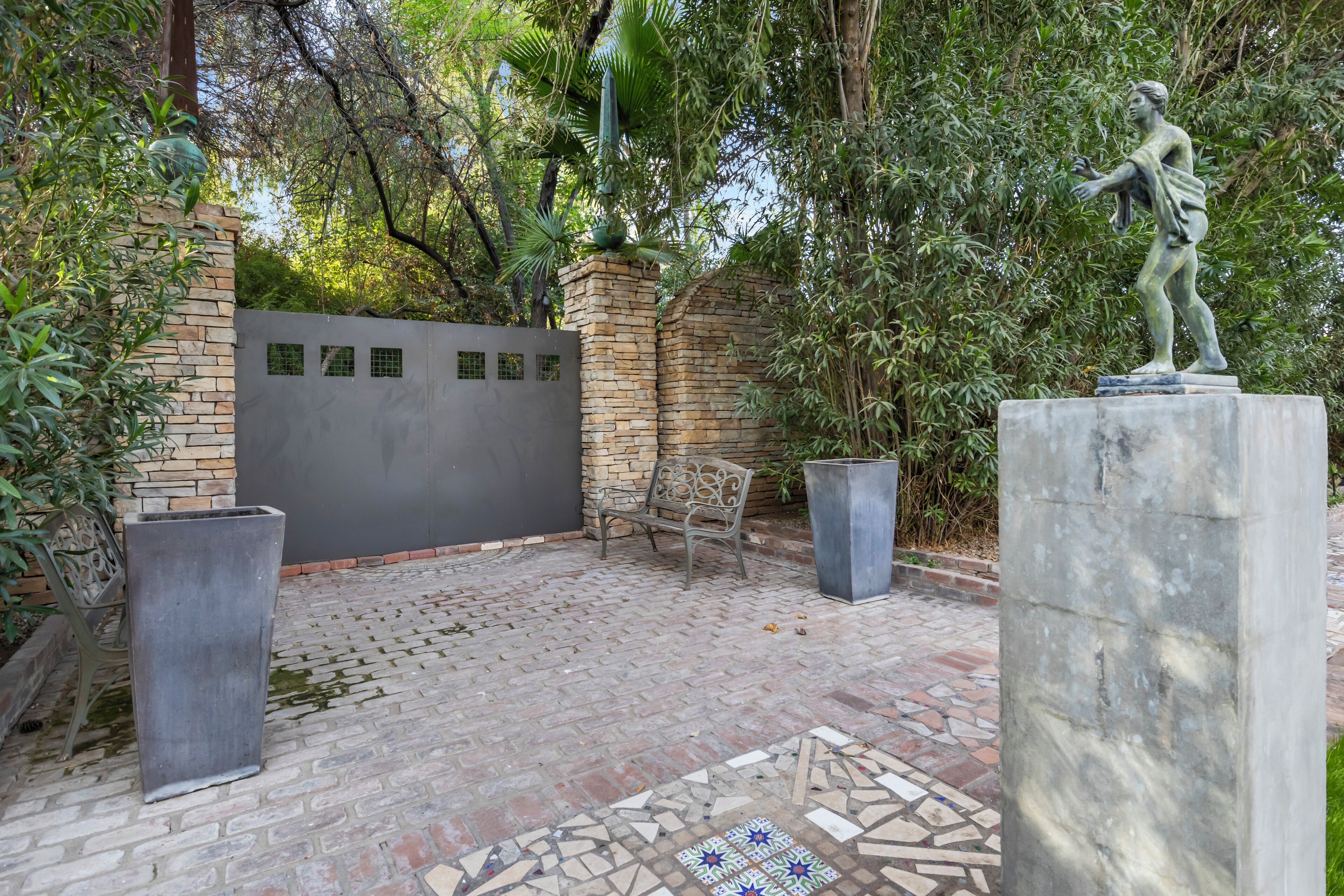 A courtyard with a statue, a bench, and a decorative wall.