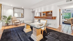 A modern kitchen with a glass dining table, wooden chairs, and a built-in microwave.