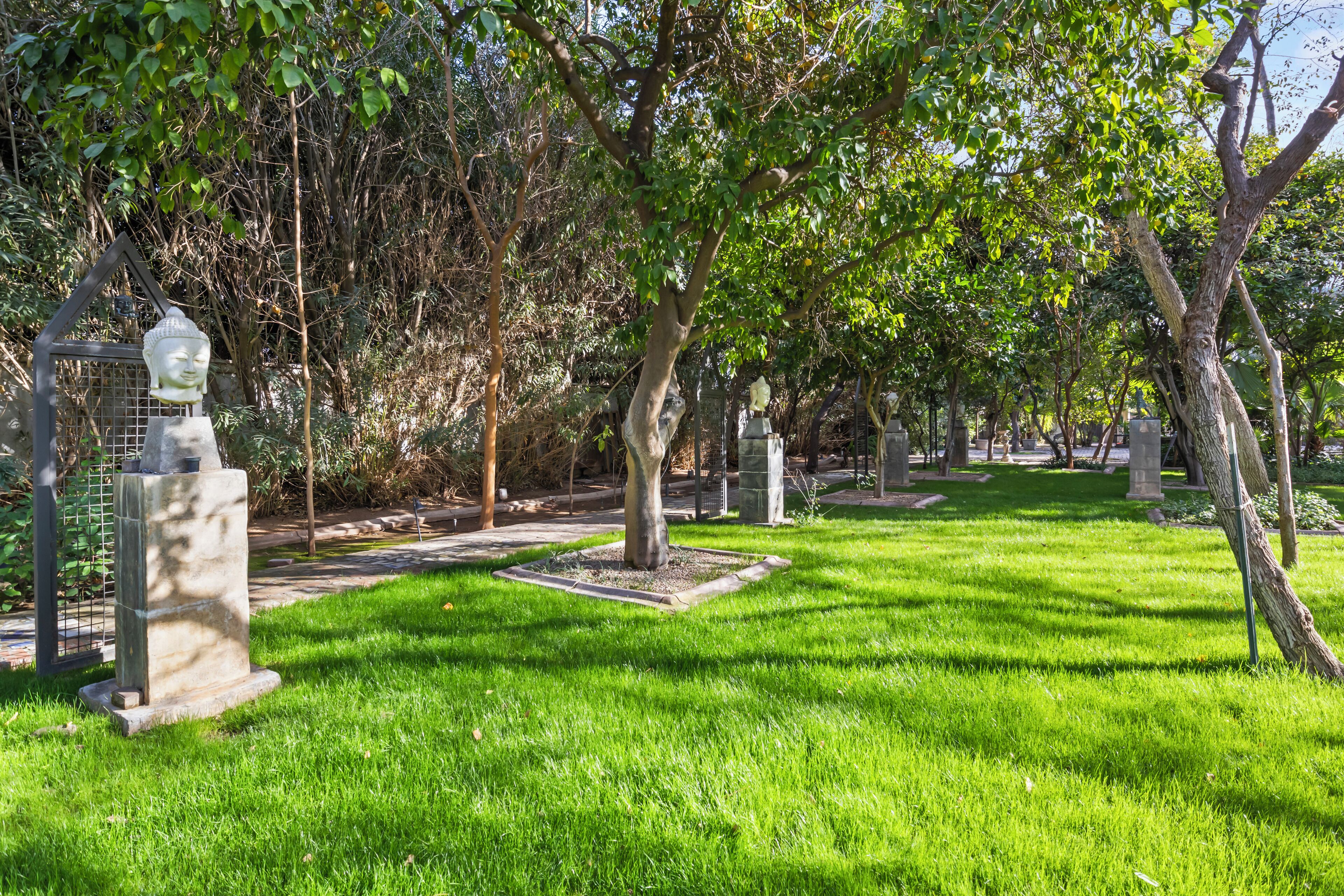 Un cementerio con césped cuidado, monumentos de piedra y árboles.