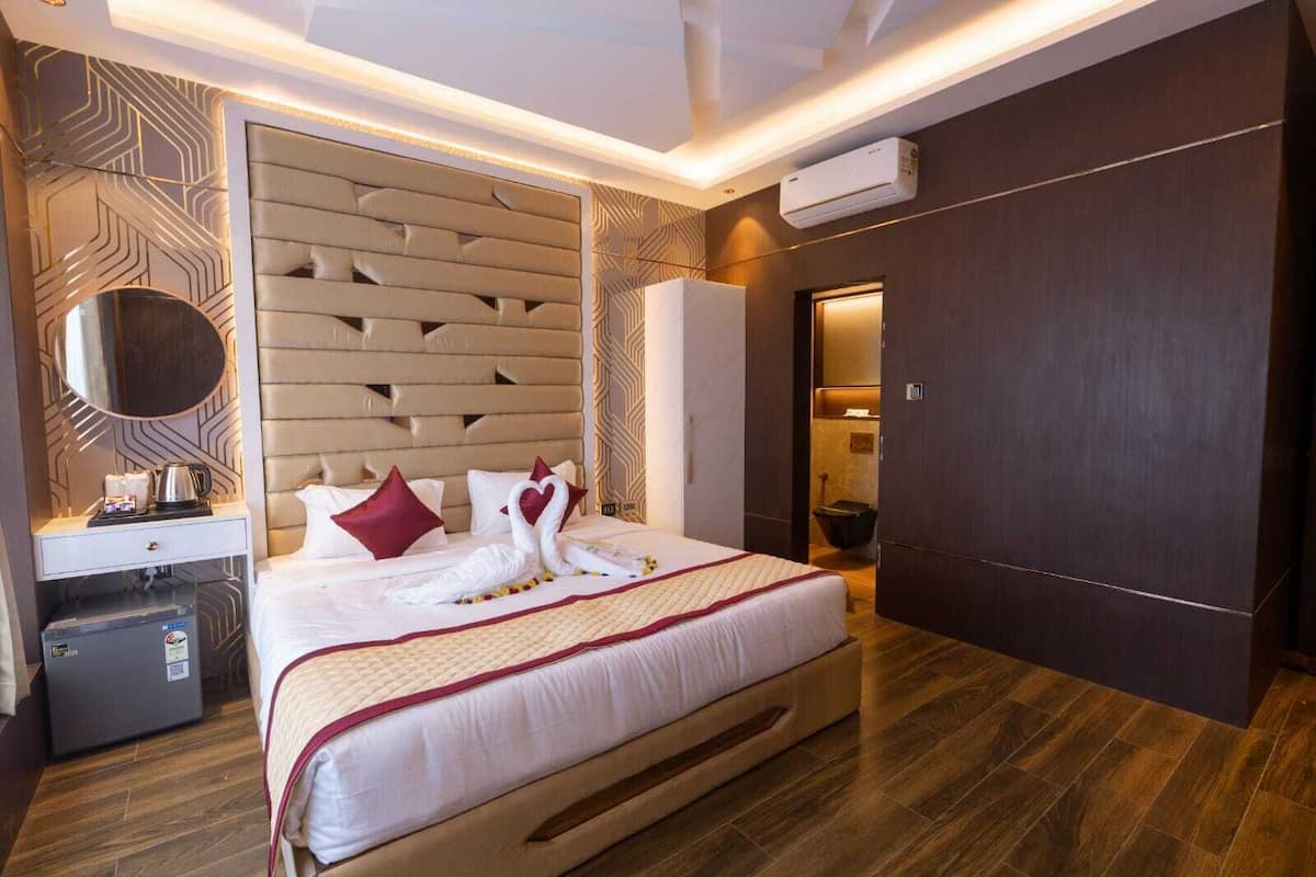 Habitación de hotel con una cama grande, una mesita de noche con tetera, un armario y un equipo de aire acondicionado.