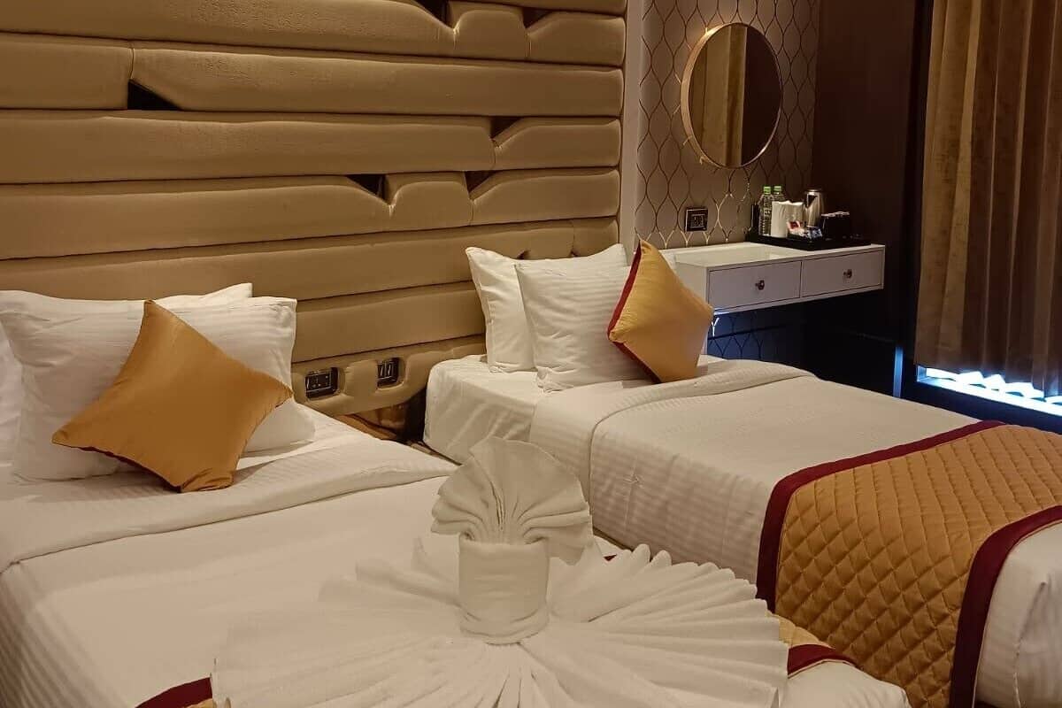 Habitación de hotel con tres camas, un tocador con artículos de aseo y un espejo.