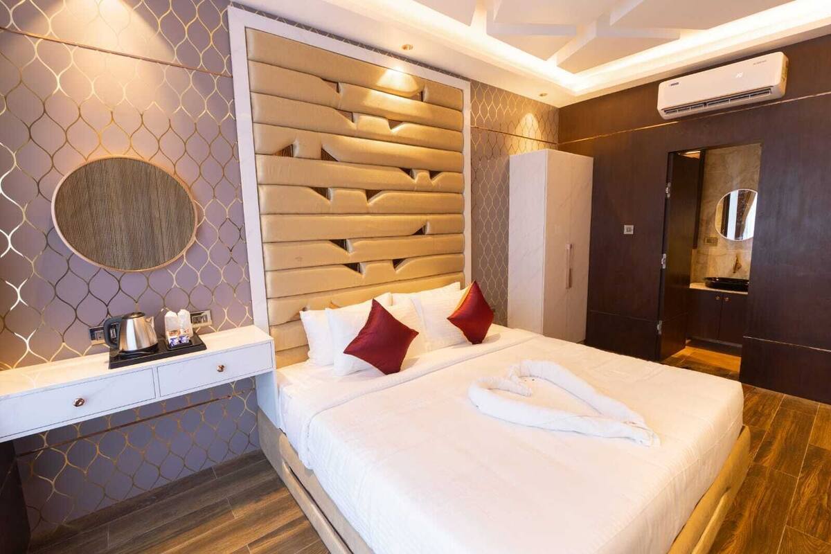 Una habitación de hotel con cama, mesita de noche y espejo.