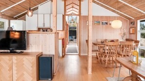 A wooden interior with a kitchen, dining area, and a TV.