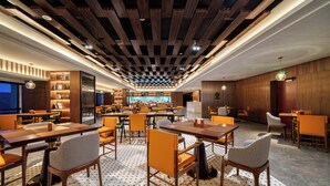 A modern restaurant with wooden panel ceilings, multiple dining tables, and chairs. - UrCove by Hyatt Quzhou Changshan (Quzhou)