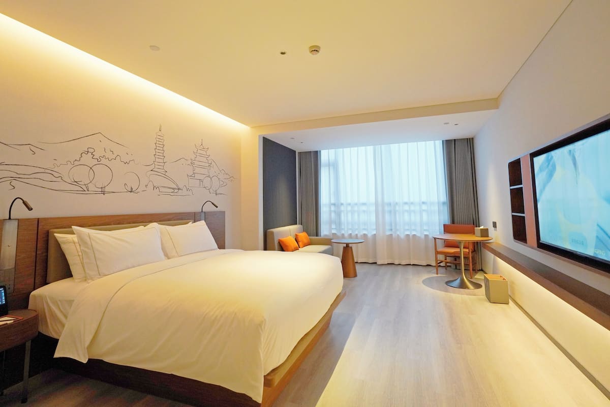Ein modernes Hotelzimmer mit einem großen Bett, einem Schreibtisch und einem Fernseher.