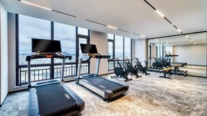 A modern gym with treadmills, exercise bikes, and weights, large windows with a city view. - UrCove by Hyatt Quzhou Changshan (Quzhou)