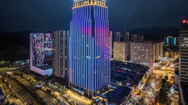 A high-rise hotel with illuminated vertical lines and a prominent sign at the top. - UrCove by Hyatt Quzhou Changshan (Quzhou)