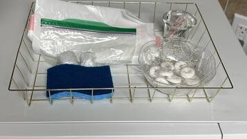 Eine Mikrowelle mit einem Glasgeschirrgestell obenauf, das eine Glasschüssel, eine Plastiktüte und ein blaues Handtuch enthält.
