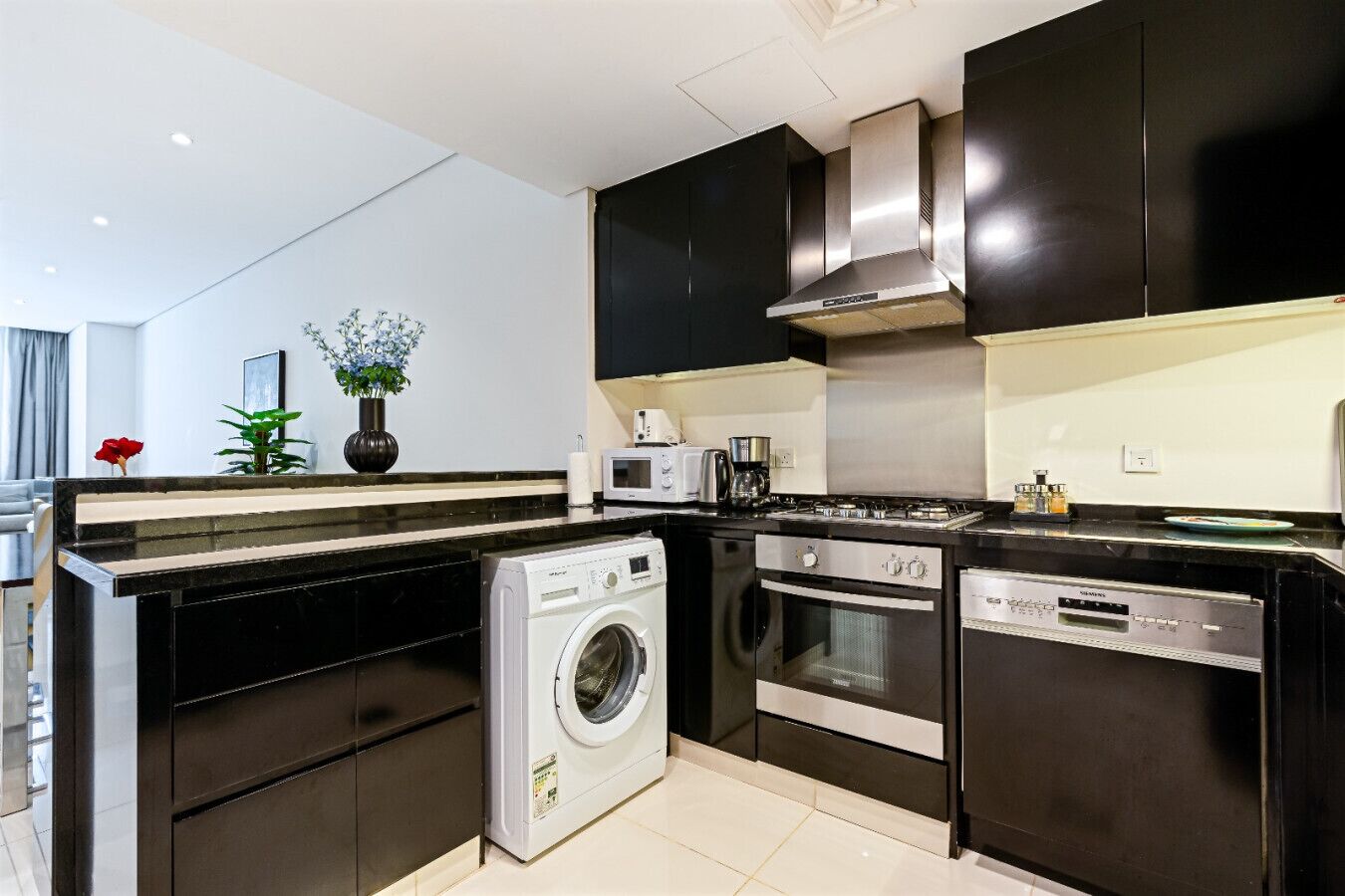A modern kitchen with a washing machine, oven, microwave, and a stove.