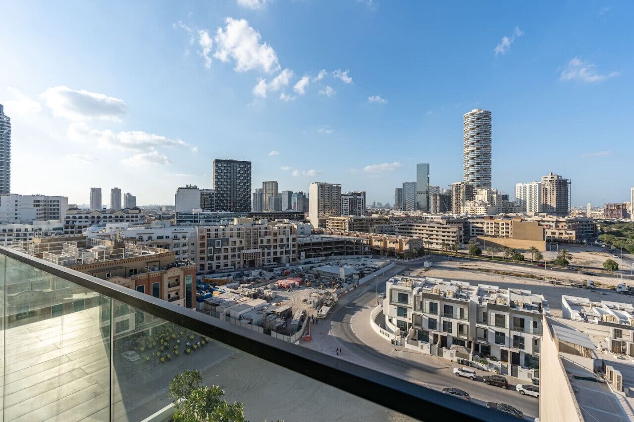 Paisaje urbano con edificios modernos de gran altura, cielo despejado y vista a un estacionamiento.