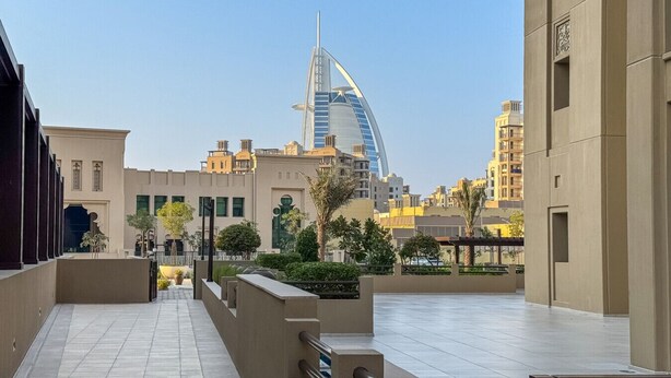 A modern urban area with a prominent curved building in the background, likely a hotel or landmark.