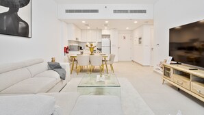 A modern living room with a sofa, a glass coffee table, and a TV stand.