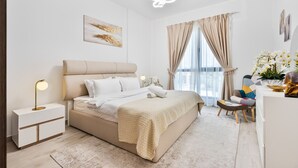 A modern bedroom with a bed, bedside table, lamp, and a view of the outdoors through large windows.