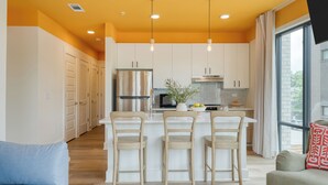 A modern kitchen with white cabinets, a stainless steel refrigerator, and a central island with bar stools. - 2 Bedroom Accessible Hotel Suite in 12South! (Nashville)