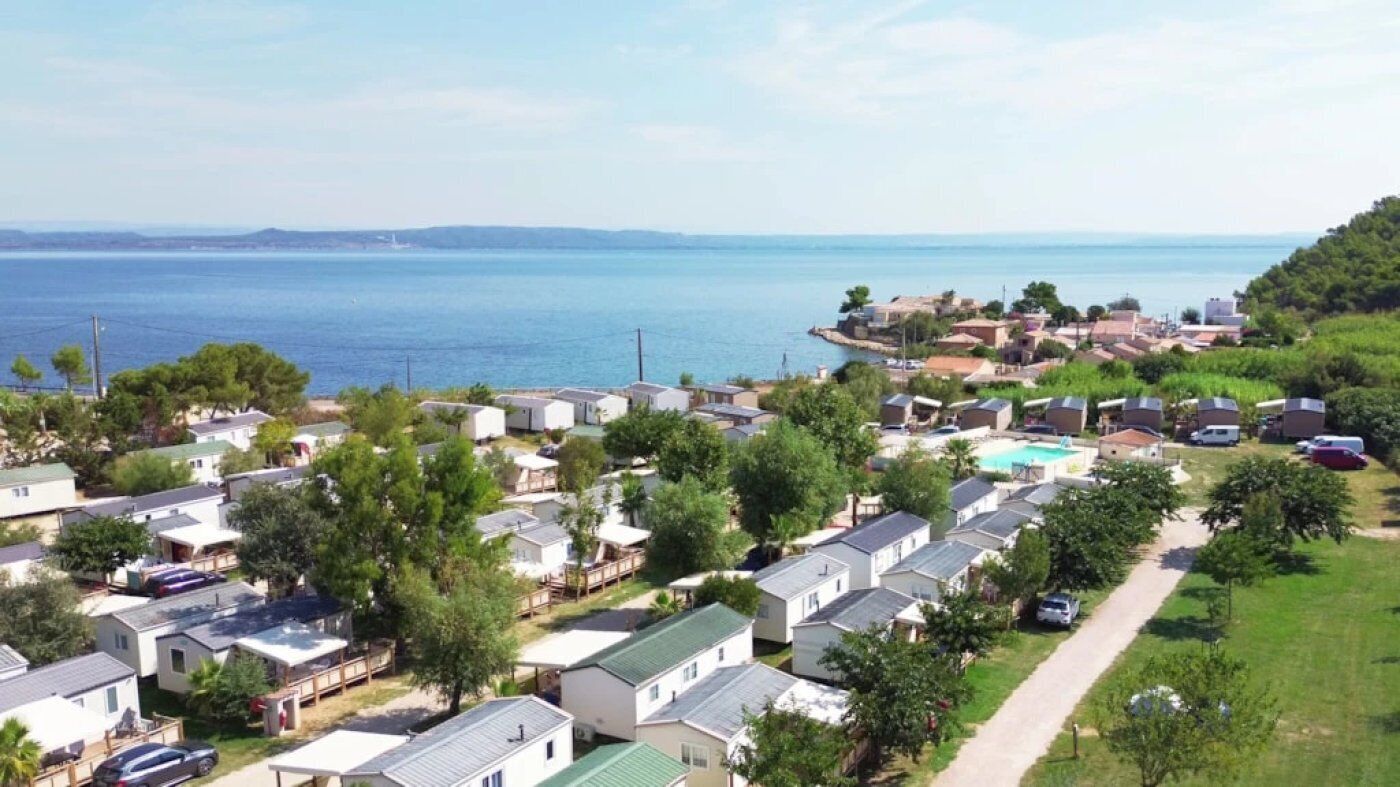 A coastal residential area with mobile homes, a swimming pool, and a view of the sea.
