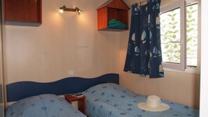 Un dormitorio con dos camas, una mesita de noche, una ventana con cortinas y un estante en la pared.