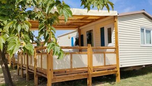 A mobile home with a wooden deck and a pergola. - ZEcamping 3* pataugeoire piscine locatif TV clim 24m2 4 pers (Saint-Mitre-les-Remparts)