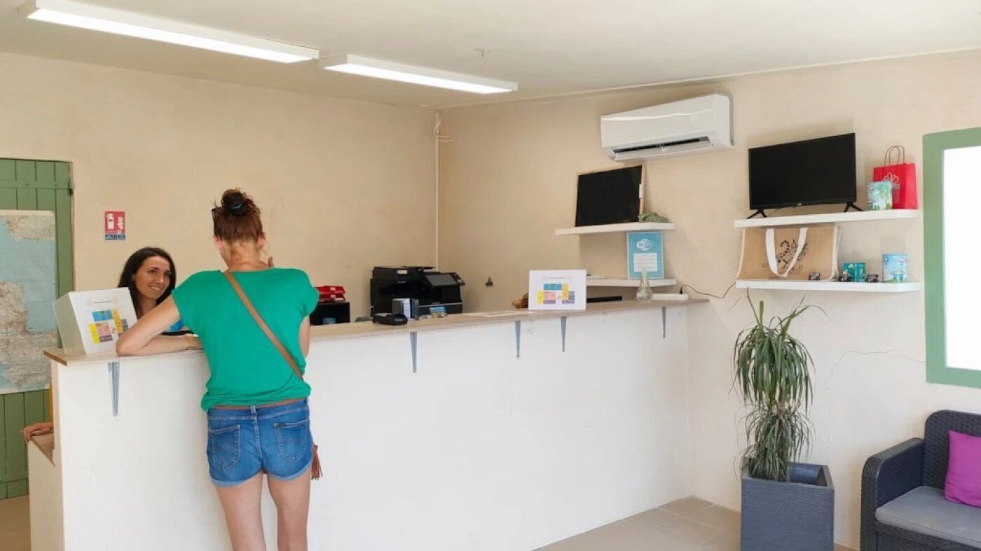 A reception area with a counter, a flat-screen TV, an air conditioner, and a plant.