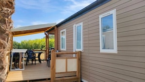 Une terrasse en bois dotée d’un espace salon couvert, d’une petite table et de chaises.