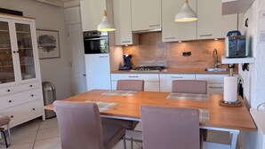 Eine moderne Küche mit weißen Schränken, einem Holztisch und einem Gasherd.