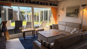 Ein Wohnzimmer mit einer Couch, einem Couchtisch, einem Sessel und einem Bücherregal.