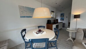 A dining area with a round table, blue chairs, and a hanging lamp.