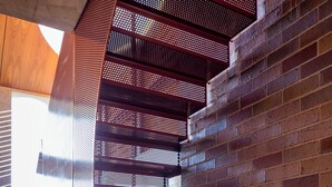 A modern architectural design with a curved metal railing and brick walls.