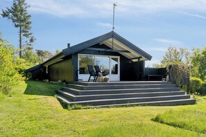 Ein modernes Haus mit einer überdachten Veranda, einer Satellitenschüssel und einer Treppe, die zum Eingang führt.