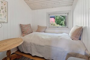 A bedroom with a bed, pillows, a window, and a wooden table. - Holiday home with peace, nature and great moments (Jægerspris)