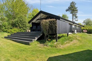 A modern cabin with a sloped roof, a small porch, and a staircase leading to the entrance. - Holiday home with peace, nature and great moments (Jægerspris)