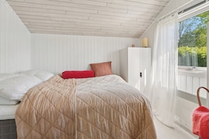A bedroom with a bed, a wardrobe, and a window with curtains.
