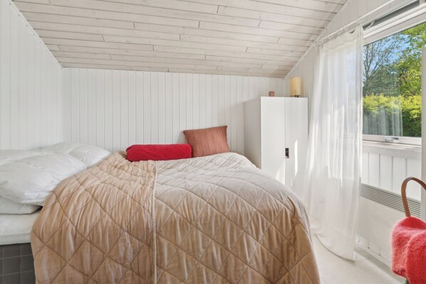 A bedroom with a bed, a wardrobe, and a window with curtains. - Holiday home with peace, nature and great moments (Jægerspris)