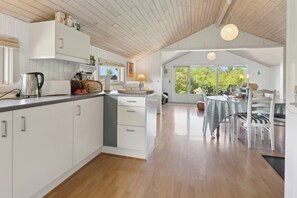 Eine geräumige Küche mit weißen Schränken, einer Holz Arbeitsplatte und einem Essbereich mit Tisch und Stühlen.
