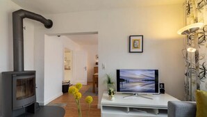 Una sala de estar con chimenea, televisor de pantalla plana, sofá y una planta decorativa.