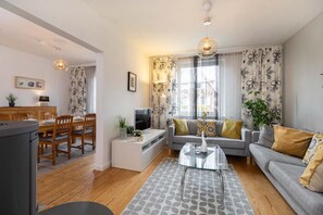 A living room with a sofa, coffee table, and dining area with chairs and a table. - Holiday Home 'Meeresbrise' with Private Terrace, Shared Garden and Wi-Fi (Lübeck Travemünde)