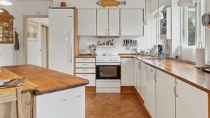 Et moderne køkken med hvide skabe, en træbordplade og en fiskepynt over skabene.