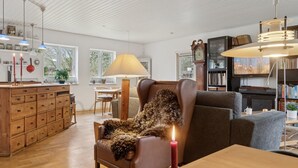En rummelig stue med et træskab, en læderarmstol, en sofa og et spisebord.