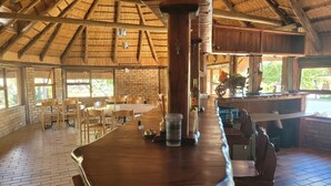 Un comedor espacioso con una larga mesa de madera, paredes de ladrillo y techo de paja.