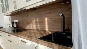 Une cuisine moderne avec des armoires blanches, un plan de travail en bois et un évier noir.