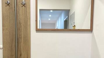 A room with a wooden cabinet, a bench with a storage drawer, and a mirror on the wall.