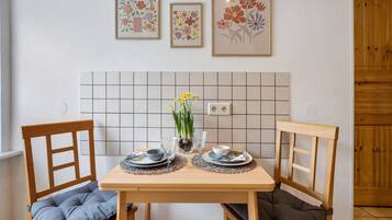Ein Esstisch mit Stühlen, eine geflieste Spritzschutzwand und gerahmte Blumenbilder an der Wand.